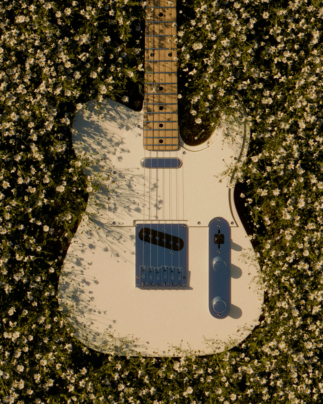 A white guitar sitting on top of a field of flowers