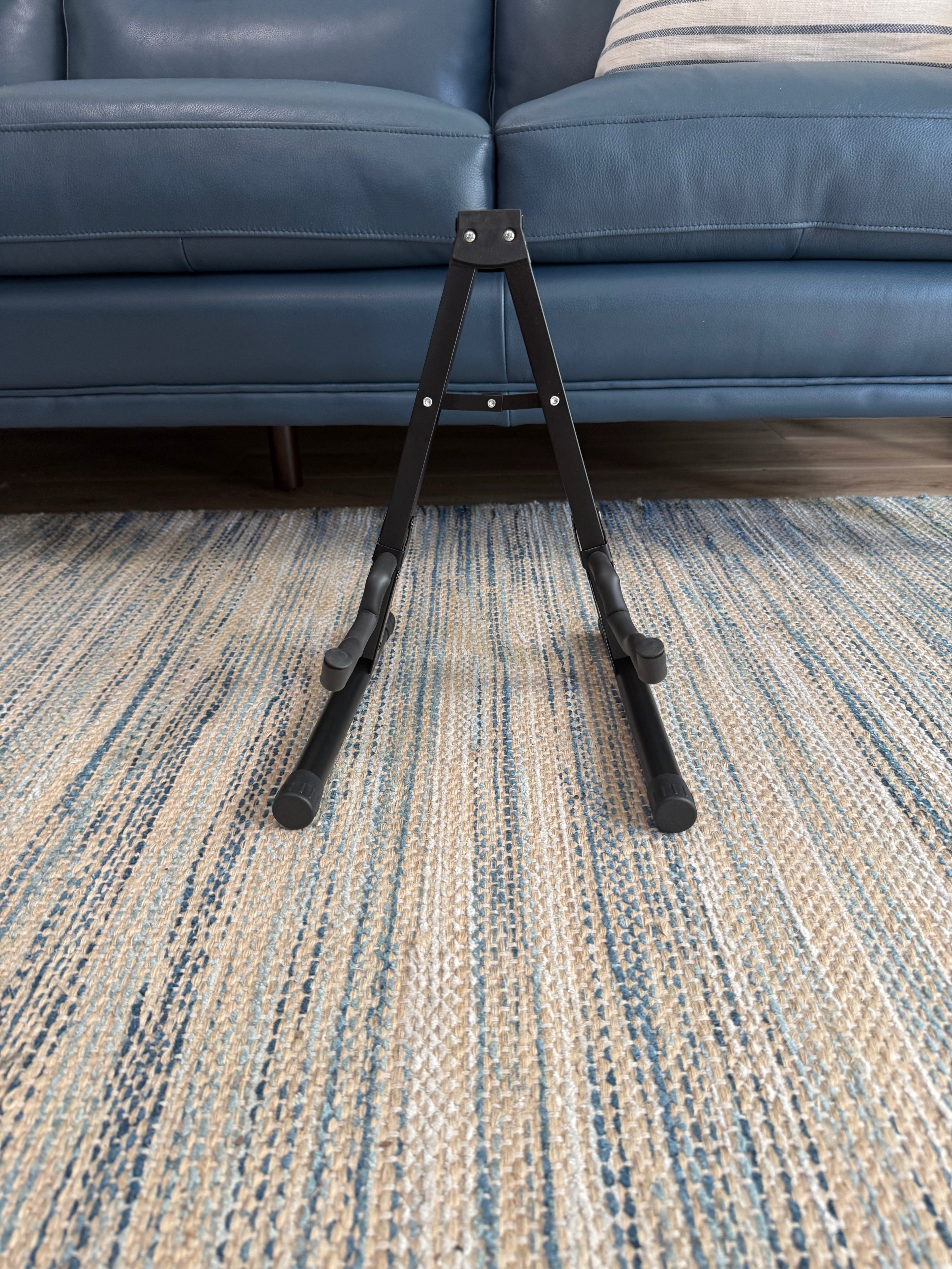 Folding A-frame guitar stand by Palm Harbor Music holding an acoustic guitar, compact and portable design for easy storage.