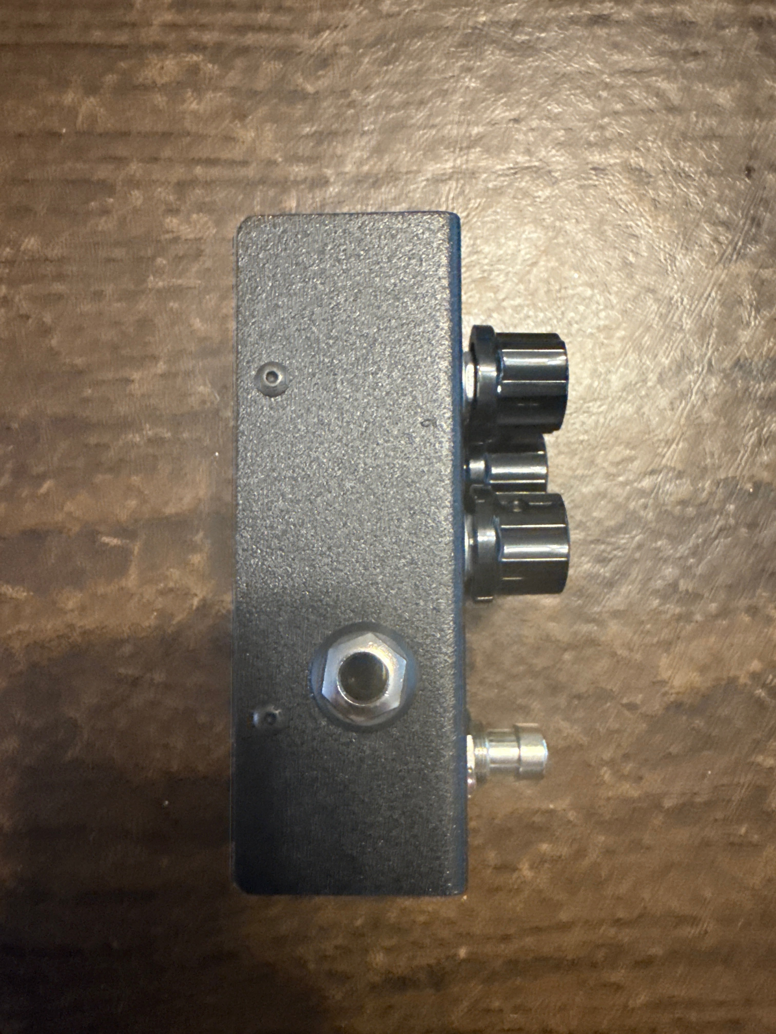 Metallic block with cylindrical components on a textured brown background