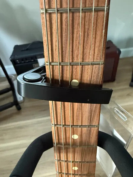 Black capo for guitars, featuring a sleek design and easy-to-use clamp mechanism, ideal for musicians and guitarists.