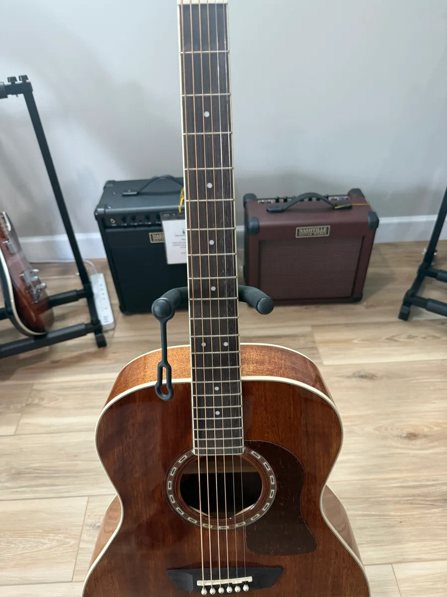 Used Washburn HG12SO WEK Heritage Acoustic Guitar with natural wood finish and classic design displayed on a stand.
